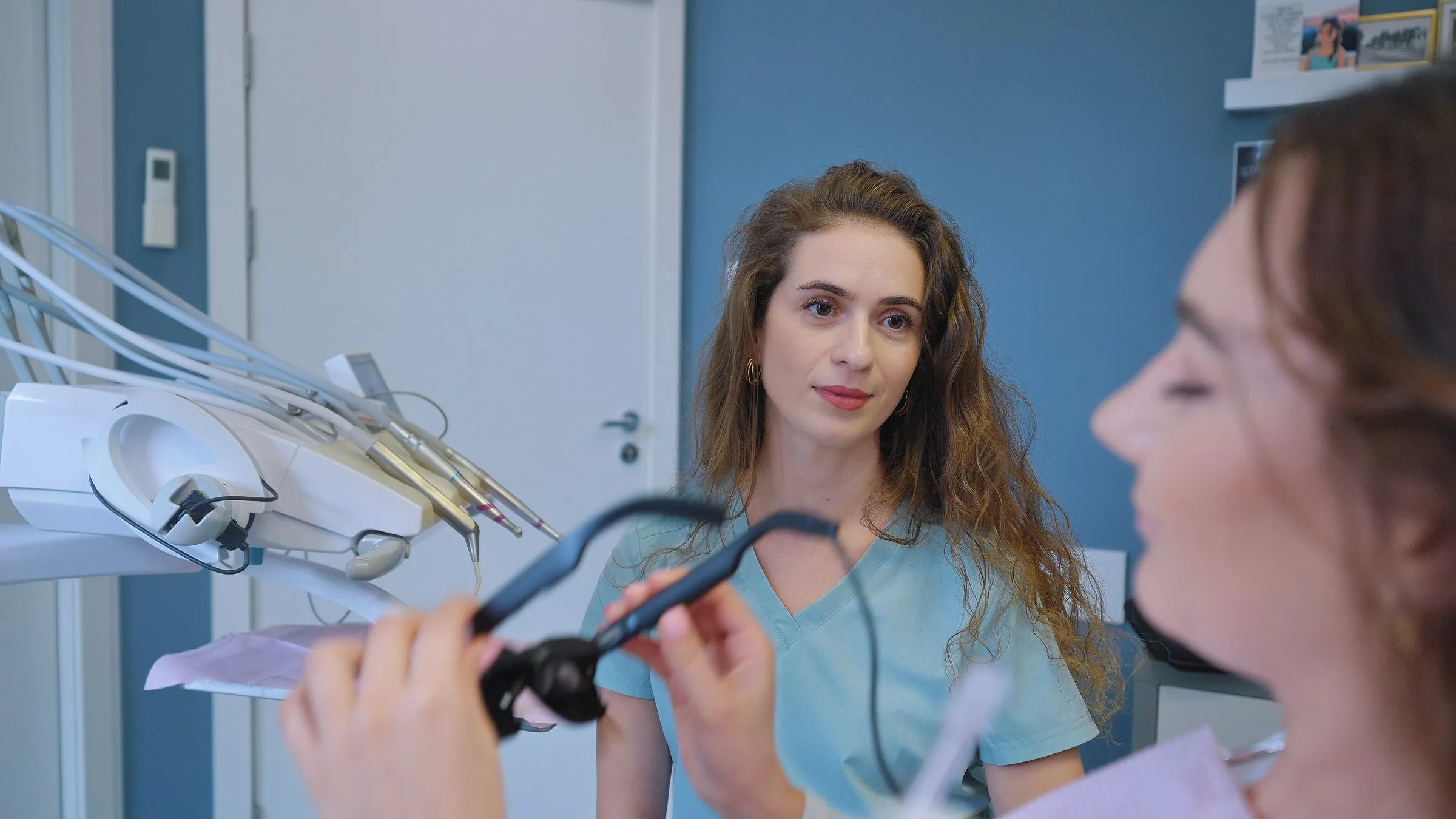 Lekarka z okularami Dental Glasses w dłoniach rozmawia z pacjentką po zabiegu