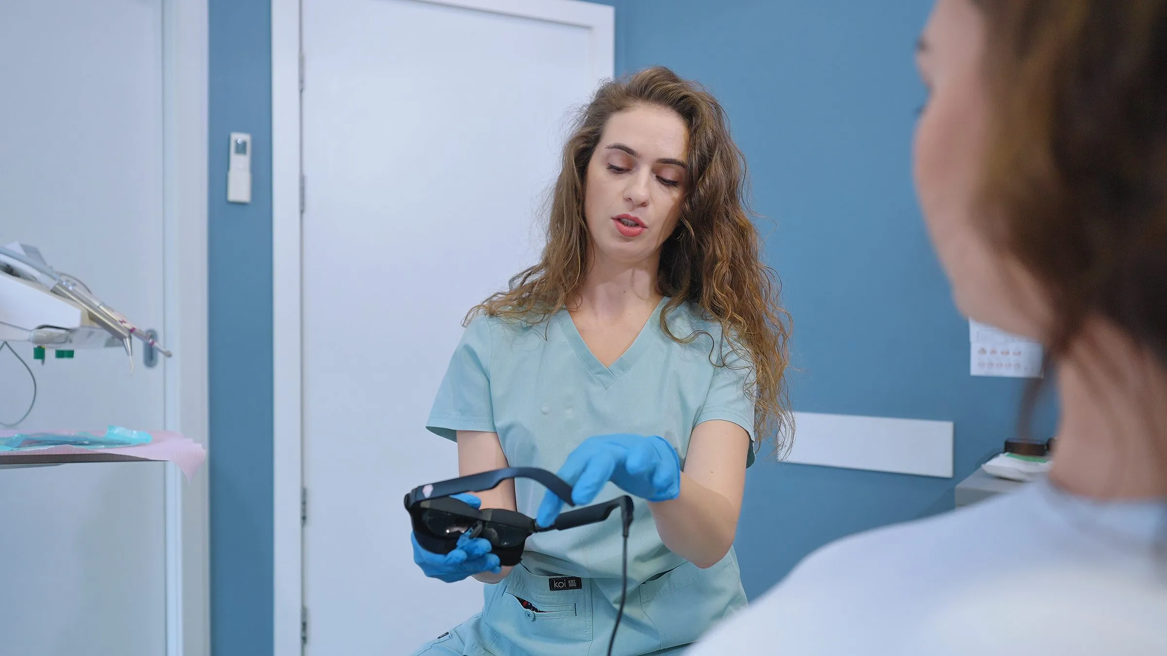 Lekarka pokazuje pacjentce okulary z ekranem Dental Glasses przed zabiegiem